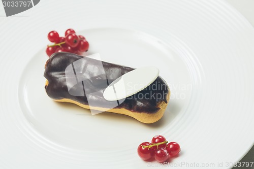 Image of Single chocolate eclair on white  plate