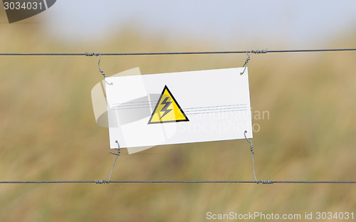 Image of Border fence - Old plastic sign with a flag