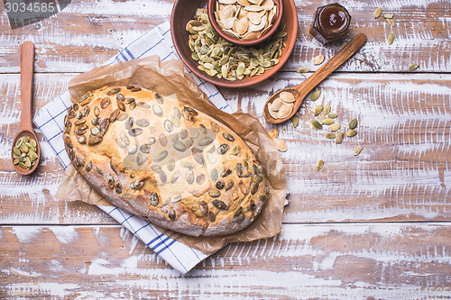 Image of Newly fledged bread with pumpkin seeds on wooden table