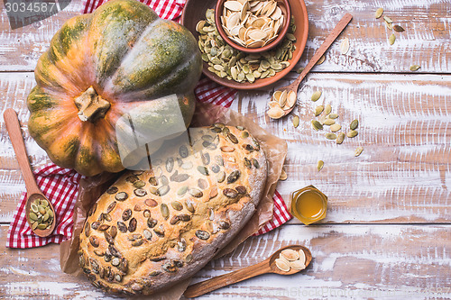 Image of Newly baked white bread with seeds and pumpkin on wood