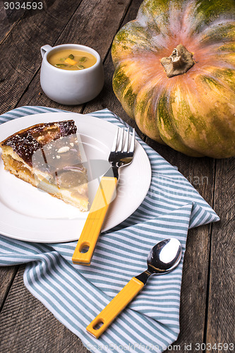 Image of Pumpkin pie with cream soup on wooden table in Rustic style