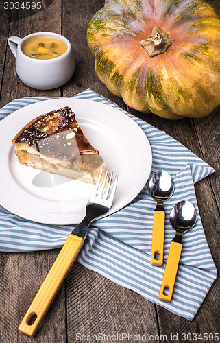 Image of piece of pie with pumpkin and cream soup on table in Rustic styl