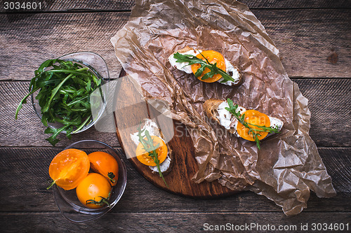 Image of Bruschetta with tomatoes and salad rocket on board in rustic sty