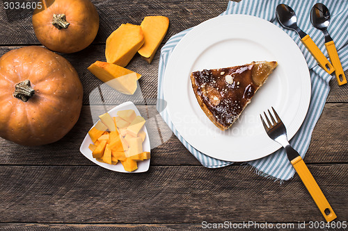 Image of Tasty pie on plate and pieces of pumpkin in Rustic style