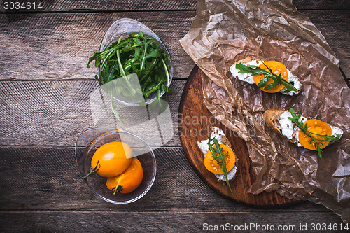 Image of Bruschetta with tomatoes and rucola on board in rustic style