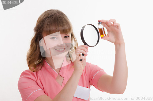 Image of Pharmacist considers the liquid through a magnifying glass
