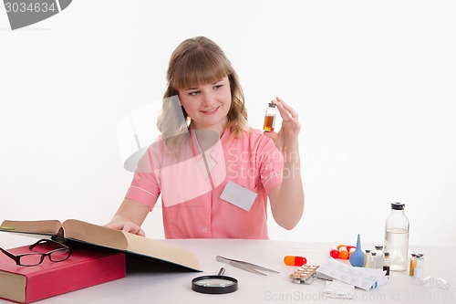 Image of Pharmacist studying under directory properties of liquid in vial