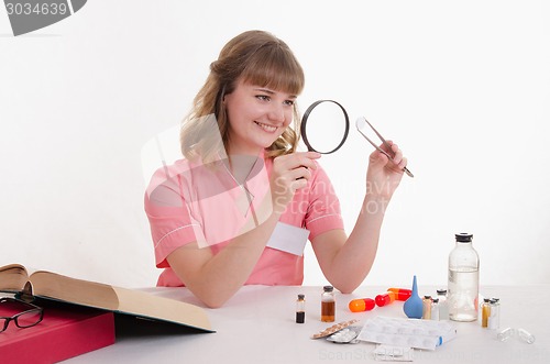 Image of Student pharmacist considers the pill under magnifying glass