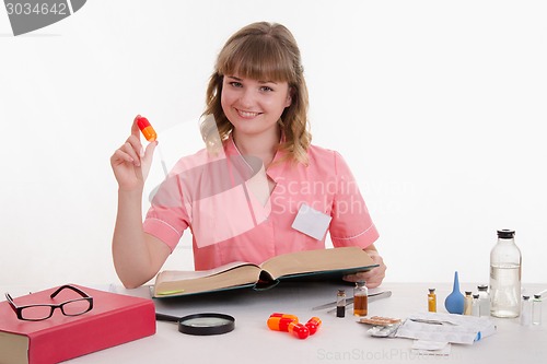 Image of Pharmacist sitting at table with the pill and reference