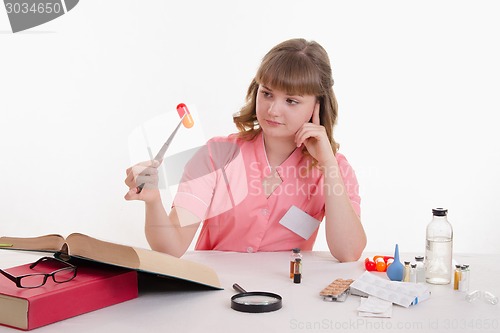 Image of Pharmacist sitting at a table with tweezers on the pill