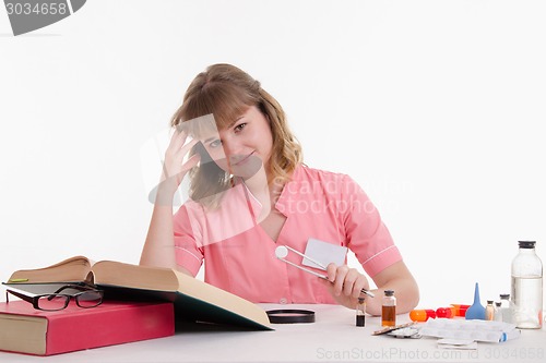 Image of Student Pharmacist delves into directory, tweezers in hand with a tablet