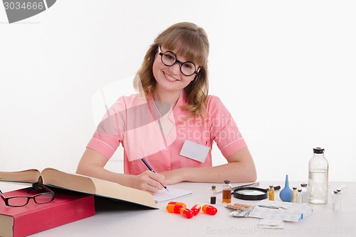 Image of Pharmacist writing in notebook sitting at a table