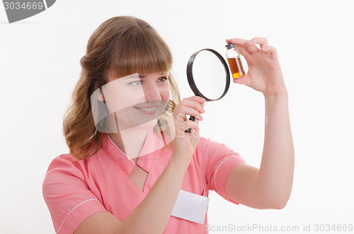 Image of Pharmacist considers the liquid through a magnifying glass