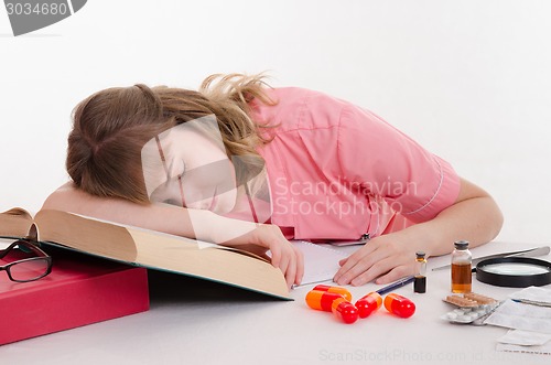 Image of Tired pharmacist sleeping on the reference