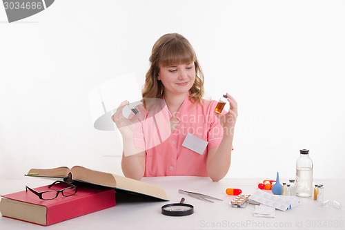 Image of Pharmacist considers two liquid in the vial