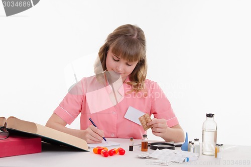 Image of Pharmacist rewrites name tablets to notebook