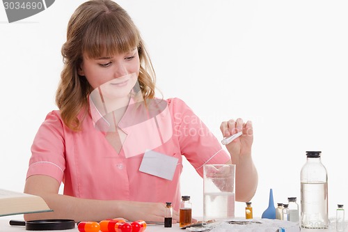 Image of Pharmacy pours white powder with a liquid in flask