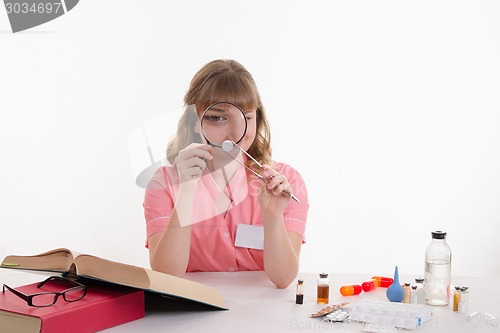 Image of The pharmacist is considering a tablet