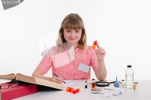 Image of Pharmacist writing in a notebook composition pills