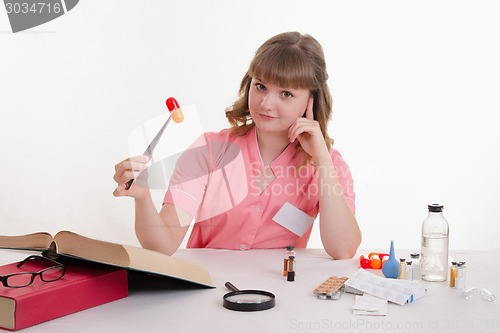 Image of Medical student sitting at a table with tweezers on the pill