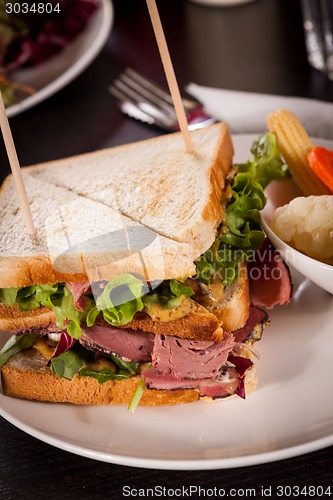 Image of Delicious pastrami club sandwich and pickles