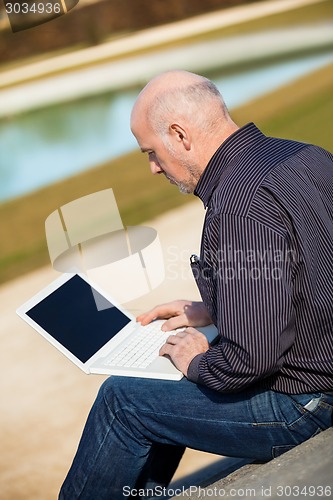 Image of Man sitting on a bench using a laptop