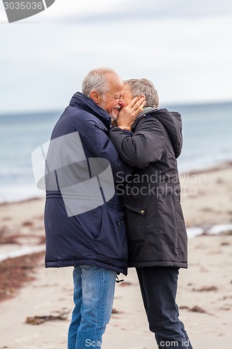 Image of happy elderly senior couple walking on beach