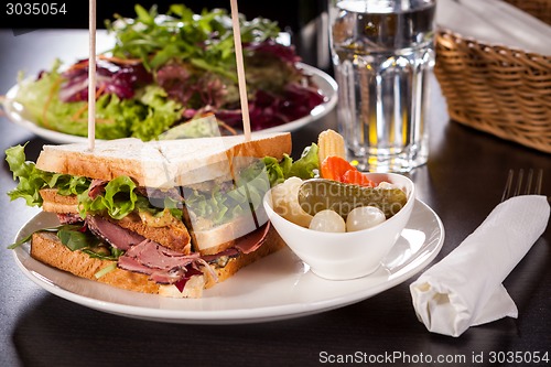 Image of Delicious pastrami club sandwich and pickles