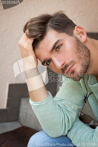 Image of Casual  young man sitting on steps