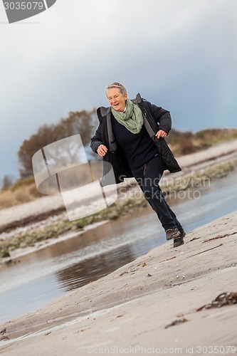 Image of Happy senior woman frolicking on the beach