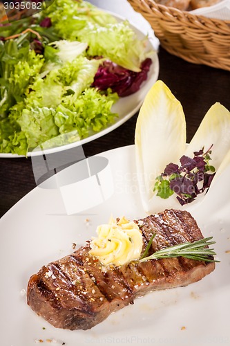 Image of Grilled beef steak topped with butter and rosemary