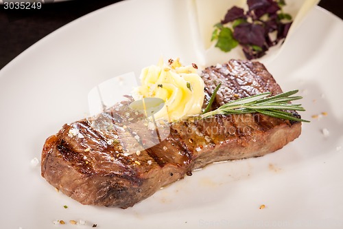 Image of Grilled beef steak topped with butter and rosemary