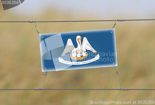 Image of Border fence - Old plastic sign with a flag