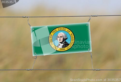 Image of Border fence - Old plastic sign with a flag