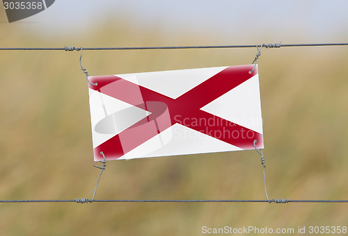 Image of Border fence - Old plastic sign with a flag