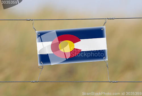 Image of Border fence - Old plastic sign with a flag