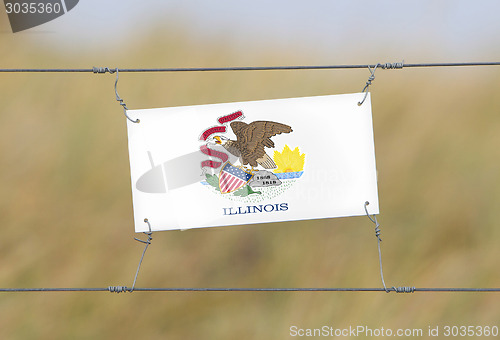 Image of Border fence - Old plastic sign with a flag