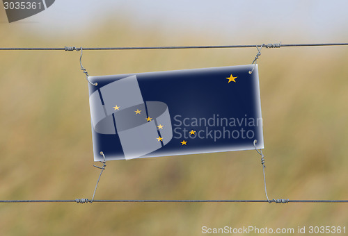 Image of Border fence - Old plastic sign with a flag