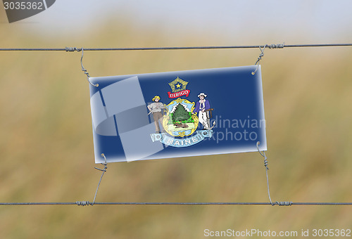 Image of Border fence - Old plastic sign with a flag