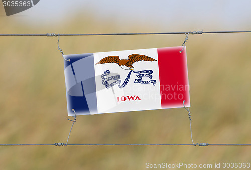 Image of Border fence - Old plastic sign with a flag