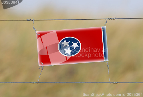 Image of Border fence - Old plastic sign with a flag