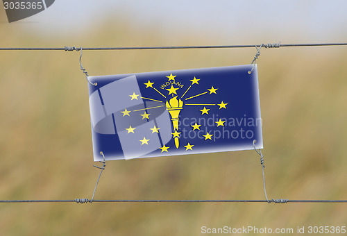 Image of Border fence - Old plastic sign with a flag