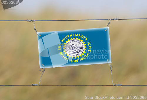 Image of Border fence - Old plastic sign with a flag