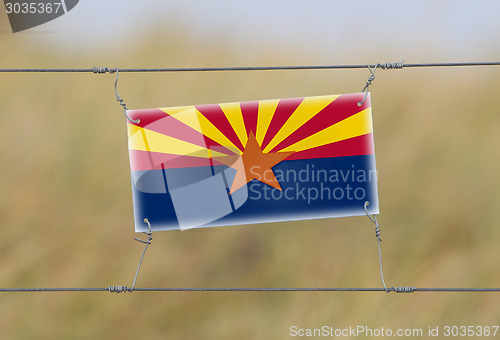 Image of Border fence - Old plastic sign with a flag