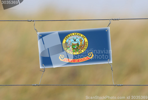 Image of Border fence - Old plastic sign with a flag