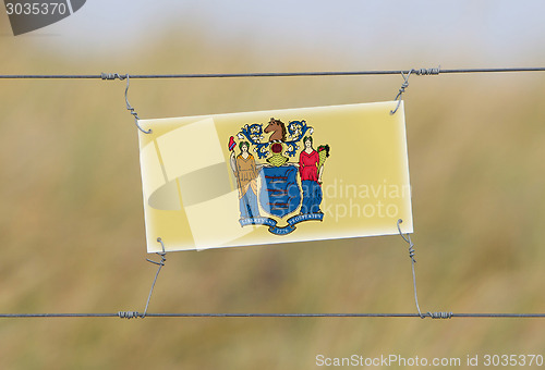 Image of Border fence - Old plastic sign with a flag