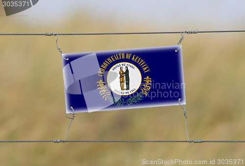 Image of Border fence - Old plastic sign with a flag