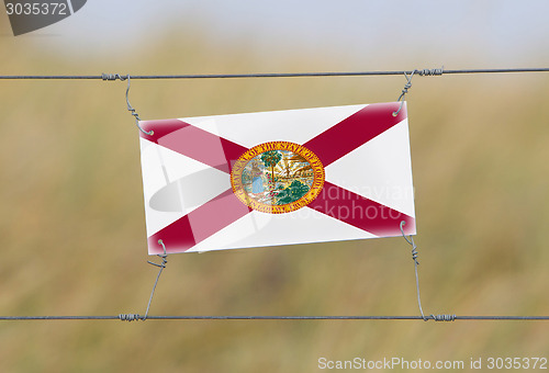 Image of Border fence - Old plastic sign with a flag