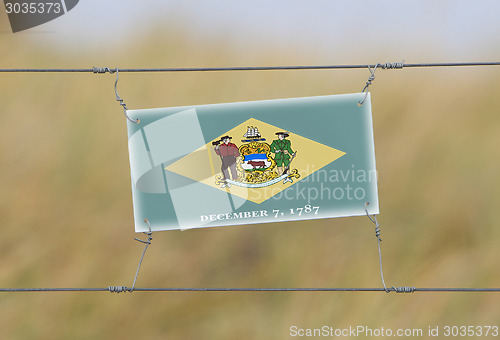 Image of Border fence - Old plastic sign with a flag