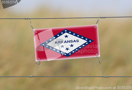 Image of Border fence - Old plastic sign with a flag